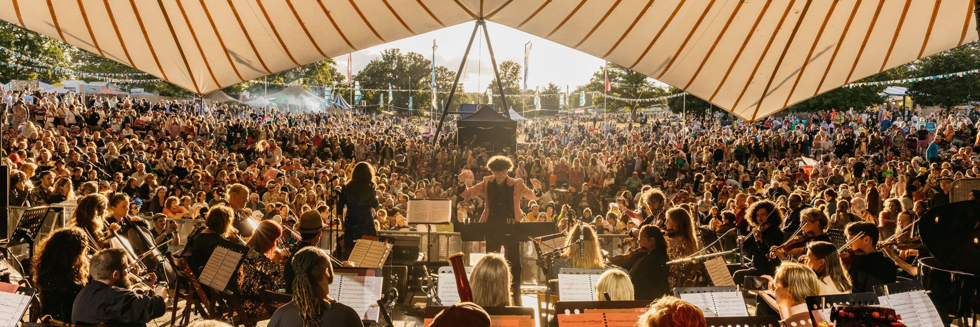 An orchestra plays to a packed crowd under the big top at Wilderness Festival